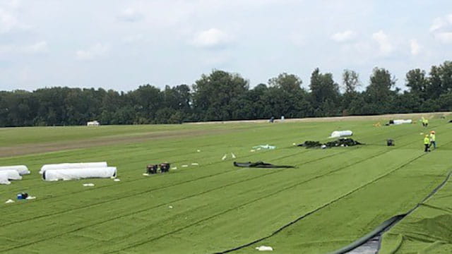 Crews finish covering the protective liner with turf and sand at Rush Island Energy Center. The cover is contoured for controlled rainwater drainage.